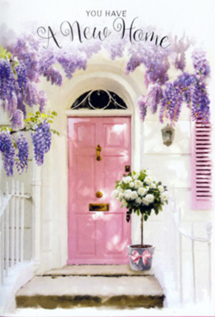 The photograph unfolds like a gentle vignette from a calm Luton street, suggesting the kind of homely scene you might discover just off Crawley Green Road or near Farley Hill. A pastel pink front door, painted in a muted, chalky tone, stands at the centre of the composition, its surface catching soft, diffused light that gives the entire entrance a warm, welcoming glow. Draped above the doorway, an abundant canopy of wisteria descends in long, tumbling trails. The blossoms are a delicate blend of lavender, lilac, and soft violet, forming clusters that look both airy and full, as if they sway lightly with each imagined breeze that passes through. The background wall is whitewashed, with a slightly mottled texture that hints at age and character, and a pale shutter beside the door echoes the pink theme, further softening the façade. Anchored on the stone step beneath all this, a rustic grey tin bucket becomes a focal point. It is packed generously with plush white and cream roses, each bloom unfurled into rich concentric layers of velvety petals. The roses nestle closely together, their rounded shapes creating a sense of luxurious fullness, while little tendrils of muted green foliage weave between them, adding depth, movement, and a touch of garden wildness. Wrapped neatly around the base of the bucket, a satin ribbon in gentle pink is tied into a simple bow, its smooth texture and slight sheen catching hints of light. The overall feeling is one of discreet celebration: a housewarming floral gift that could easily be waiting at the door of a newly purchased Luton home, quietly conveying love, encouragement, and the promise that this once-empty space will soon be filled with life, laughter, and cherished memories.